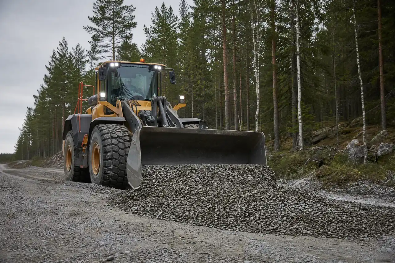 Grävmaskin som arbetar med vägentreprenad på grusväg i Hälsingland